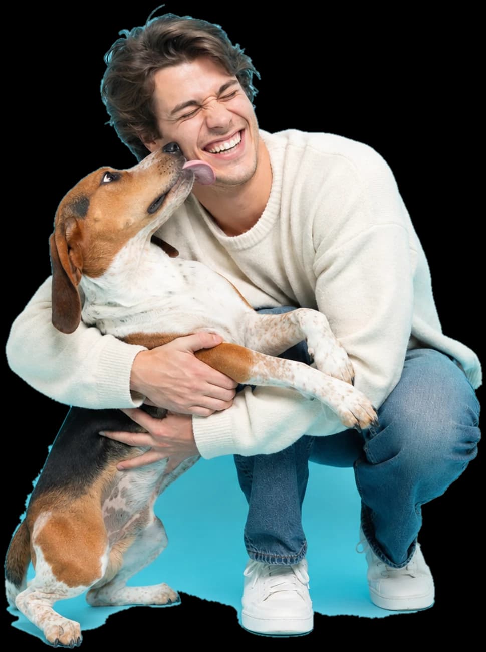 A laughing young man getting licked on the cheek by the coonhound he is hugging.